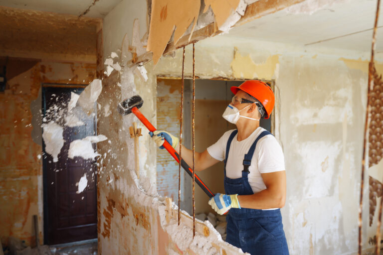 Young male builder in hard hat holding tools. Apartment repair and renovation concept