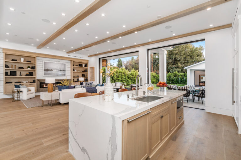 a large kitchen with a marble island and sink and living room